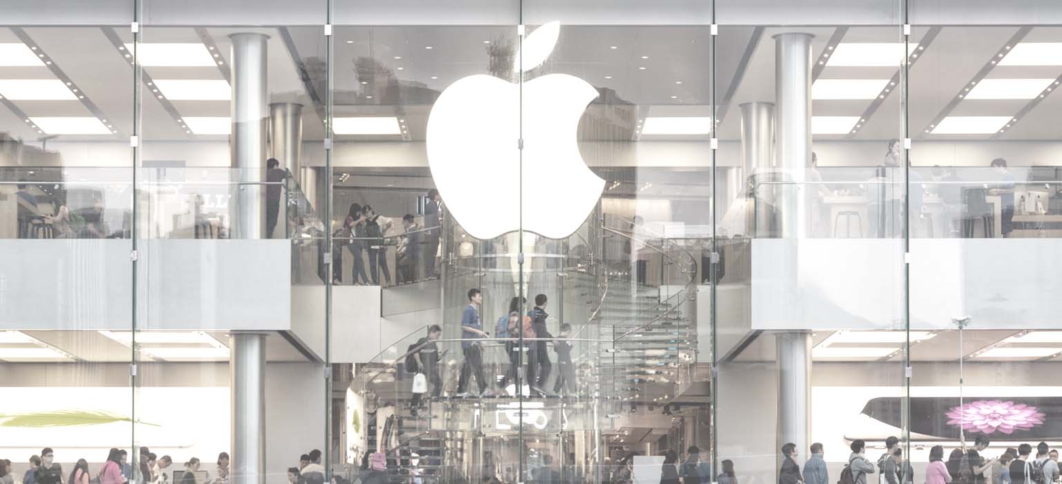 A crowded Apple store behind the facade of a huge Apple logo