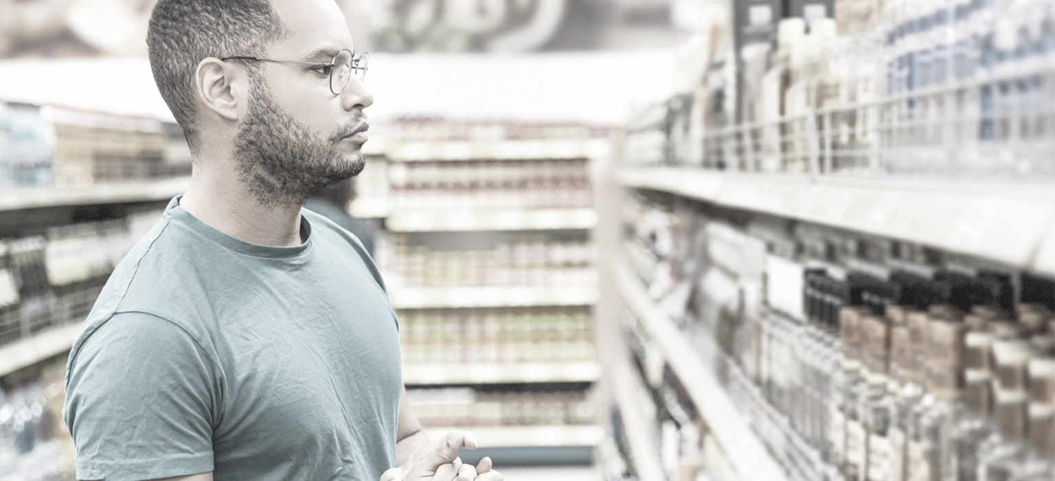 A man at the grocery store tries to decide between differently positioned brands