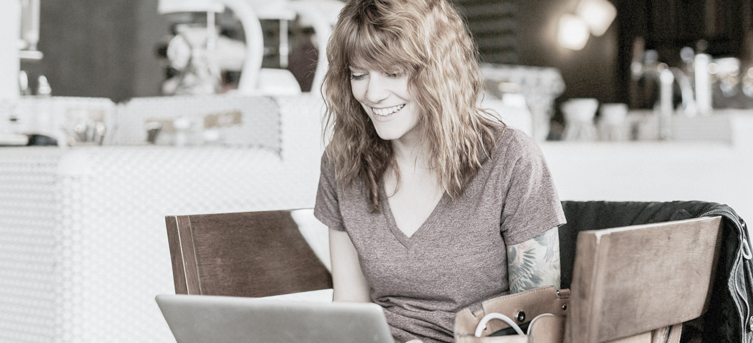 A woman smiles at her laptop during a positive brand experience